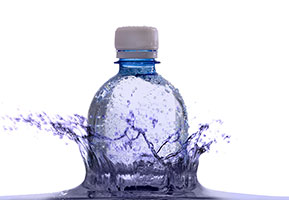 Clear plastic water bottle emerging from water and creating a splash