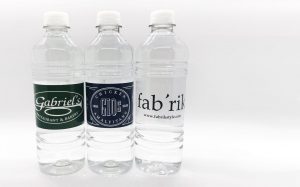 Three clear plastic water bottles with custom labels