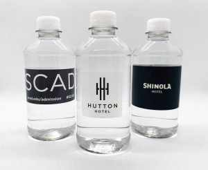 Three clear plastic water bottles with custom labels